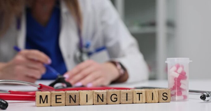 Wooden blocks show word Meningitis near pills and vials. Woman doctor in white coat writes notes checking patient treatment plan at appointment
