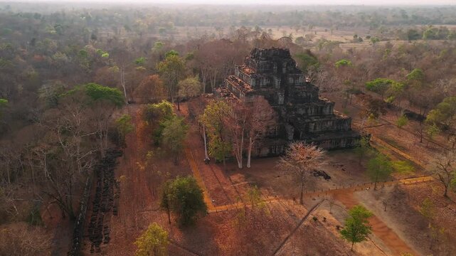 Aerial view of the ancient stone pyramid of koh ker temple complex, surrounded by dry jungle forest, Cambodia.