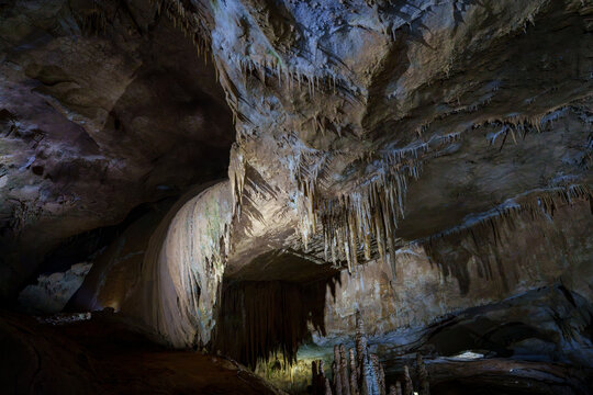 Wide cave chamber with curtain flowstone and delicate stalactites