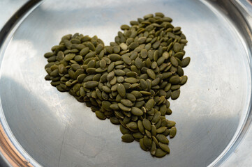Heart-shaped pile of shelled pumpkin seeds – healthy food concept