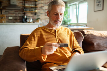 Mature man serious while making online payment at home
