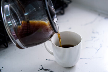 Coffee being poured into white coffee cup.