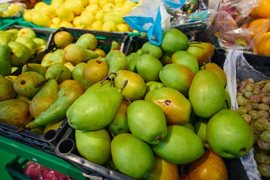 Bright green and yellow pears are arranged in bins at a local market