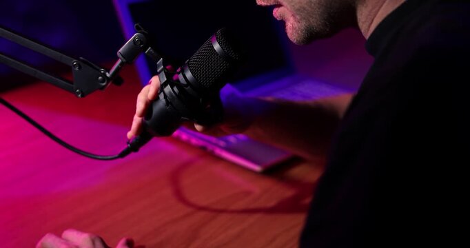 man talking in microphone in broadcasting studio with neon lights. podcast recording, streaming - Powered by Adobe