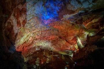 Colorfully lit cave ceiling with red and blue mineral formations