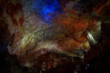 Colorfully lit cave ceiling with red and blue mineral formations