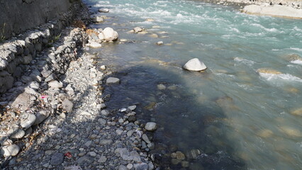 High-angle of rushing mountain river with turquoise-white water flowing over rocky terrain, rapids concept.