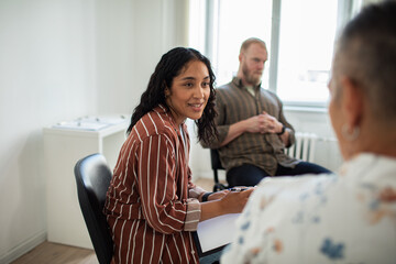 Adult woman facilitating supportive group therapy in bright office