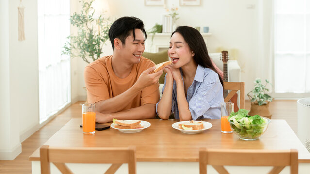 Couple Enjoying Breakfast With Fresh Juice and Sandwiches in a Bright Kitchen Setting