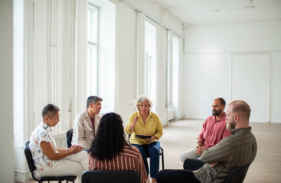 Adult and mature people in focused support group at bright community center