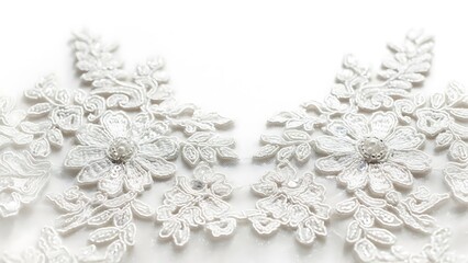 Close up of white floral lace with pearl embellishments on a white background