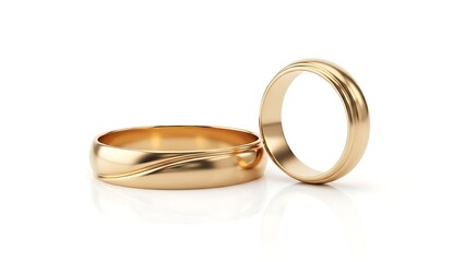 Two golden wedding bands resting on a white surface in a studio setting