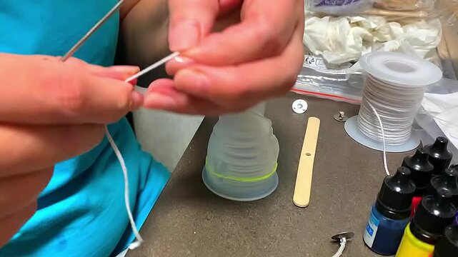 Candle making. Inserting the wick into the mold.