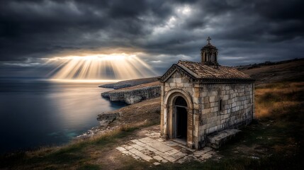 Ancient stone chapel on coastal cliff overlooking stormy sea with dramatic sunrays high resolution photo