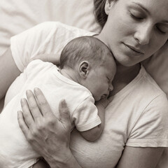 Mother peacefully lying down with her newborn baby sleeping on her chest in a serene atmosphere