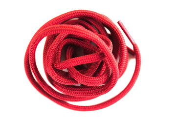 A bright red shoelace is tightly coiled, displaying its woven texture. The clean white background highlights the vibrant color, making it ideal for use in crafts or footwear design