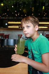 Boy child drinking green juice with straw