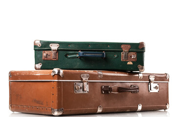 Two vintage suitcases, one green and one brown, are stacked on top of each other against a white background. These travel bags reflect stories of past journeys and adventures