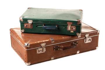 Two classic suitcases, one green and one brown, stacked together. The luggage features metal clasps and worn edges, suggesting travel history and timeless style