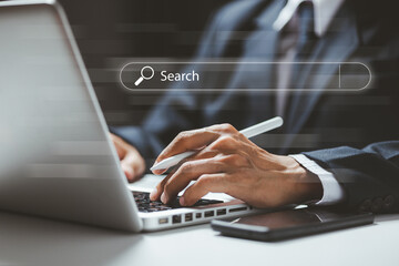 Businessman using a laptop with a digital search bar interface, symbolizing online research, data searching, SEO, and modern information technology for corporate workflows and digital marketing.