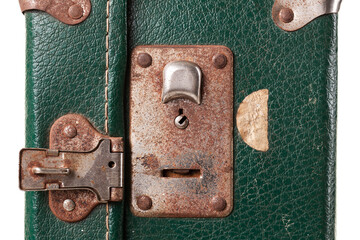 Close-up view of a vintage green suitcase lock displaying rusted metal parts and signs of aging. The lock mechanism invites curiosity about its history and travels
