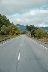 Open, empty scenic road cutting through lush autumn forest towards the horizon, C&aacute;ceres, Spain.