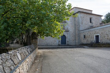 Empty courtyard of a historic stone hermitage building with arched blue door, Cáceres, Spain.