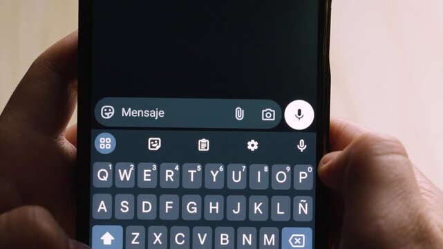 Close-up of a person holding a smartphone while writing the message &ldquo;Lo siento :(&rdquo; in a chat application. The keyboard and send button are clearly visible as the user types.