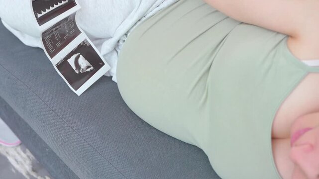 Pregnant woman sitting on a couch using her smartphone in a relaxed home setting. A calm everyday moment highlighting modern maternity lifestyle, comfort, and digital communication during pregnancy. S