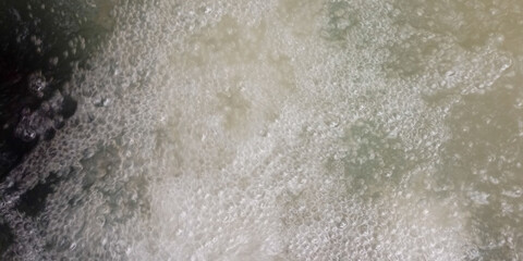 Bubbling water surface with white foam and agitated liquid