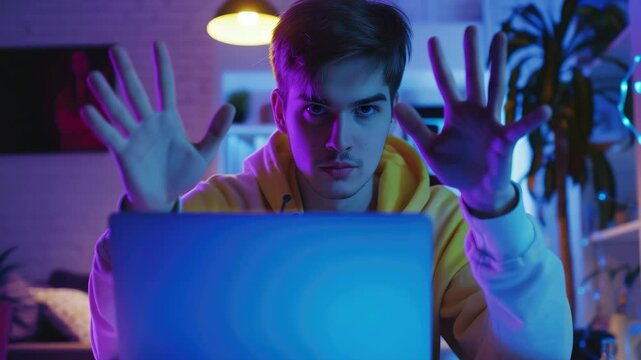 Man in dark room with open laptop, gesturing with hands in front of screen. - Powered by Adobe