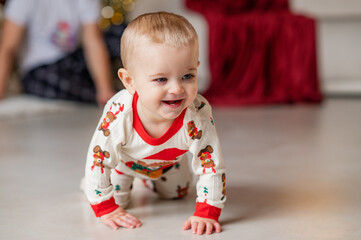 A one-year-old baby crawls on all fours, dressed in a New Year's outfit, crawling around a New Year's-decorated room, smiling. New Year and Christmas. Parenting. Family
