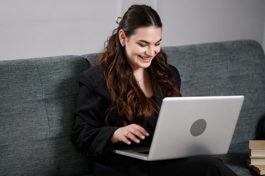 Friendly online specialist, confident consultant. During remote video conference at home, woman uses laptop for effective communication in relaxed atmosphere of home office.