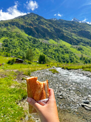 hand holding a sandwich in a mountain pass on a Summer Day 
