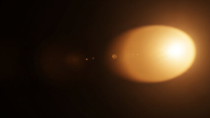 Abstract warm golden orange lens flare effect overlay on a dark black background, creating a bright luminous circle of light with subtle internal reflections and bokeh