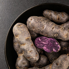 Purple potatoes raw fruit blue potatoe vegetable dish fresh gourmet food background on the table rustic food top view copy space keto and paleo diet vegan and vegetarian food