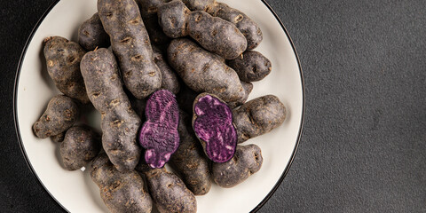 Purple potatoes raw fruit blue potatoe vegetable dish fresh gourmet food background on the table rustic food top view copy space keto and paleo diet vegan and vegetarian food