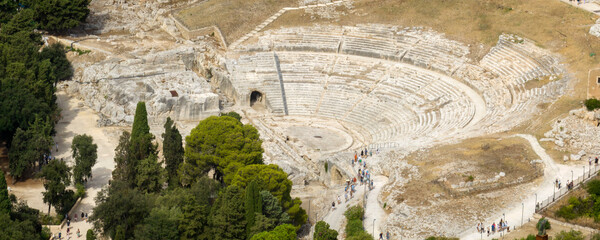 Aerial closeup of the Greek Theater of Syracuse, Italy. It is a Greek amphitheater located within the Neapolis Archaeological Park in Sicily. It is a monument of the ancient Greek colony. Sunny day.