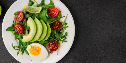 Avocado salad arugula, egg, tomato, mixed greens, vegetables dish fresh delicious gourmet food background tabletop rustic food top view copy space keto and paleo diet vegetarian food
