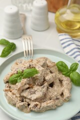 Tasty beef Stroganoff with basil on white table, closeup