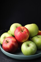 Fresh red and green apples on dark textured table against black background, closeup. Space for text