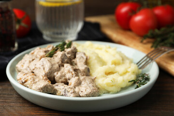 Delicious beef stroganoff with mashed potatoes and thyme served on wooden table, closeup