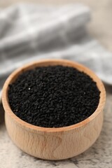 Aromatic black caraway in wooden bowl on grey table, closeup