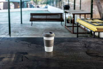 Naklejka premium Coffee cup on a wooden table in an outdoor cafe setting