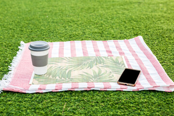 Relaxing picnic setup with coffee and smartphone on green grass