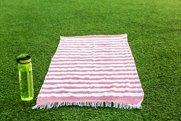 Striped towel on grass with water bottle ready for a summer picnic