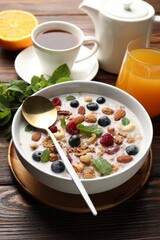 Healthy breakfast. Oatmeal with nuts, berries and milk in bowl on wooden table, closeup