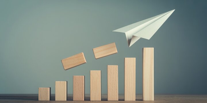 Ascending paper airplane soaring above bar graph showing growth potential and upward trend - Powered by Adobe