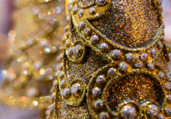 Christmas tree decoration closeup in gold, sparkles and another tree in bokeh background.