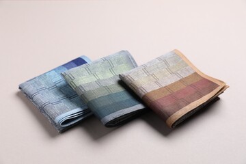 Different stylish fabric handkerchiefs on beige background, closeup